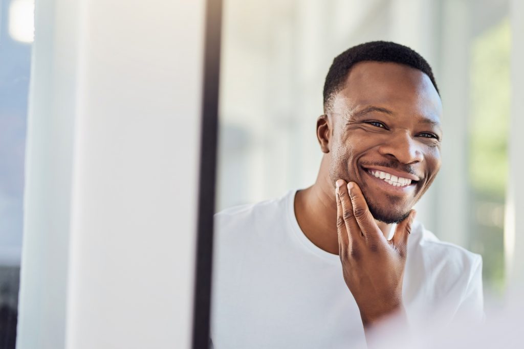 handsome young man examining his face in the bathroom mirror