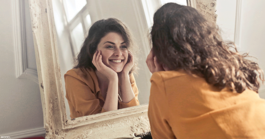 Woman looking in the mirror and smiling after wrinkle treatment