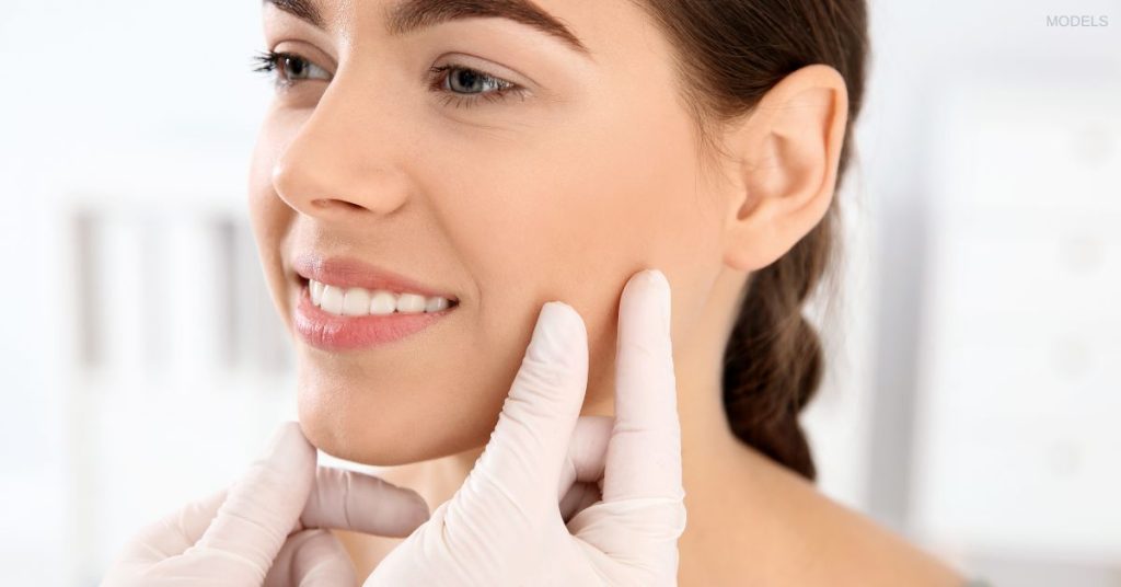 Woman having her face examined by a doctor's hands (models)