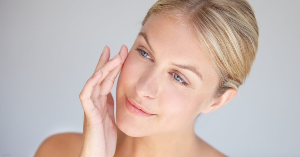 A woman touching her face and looking at the camera (model)